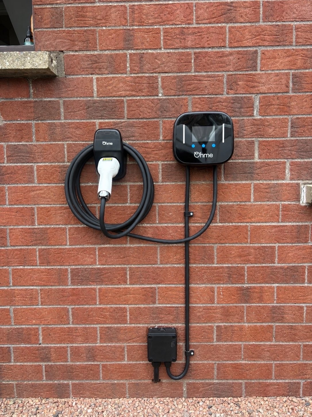 Home EV charger installed by TM Electrical on an exterior brick wall